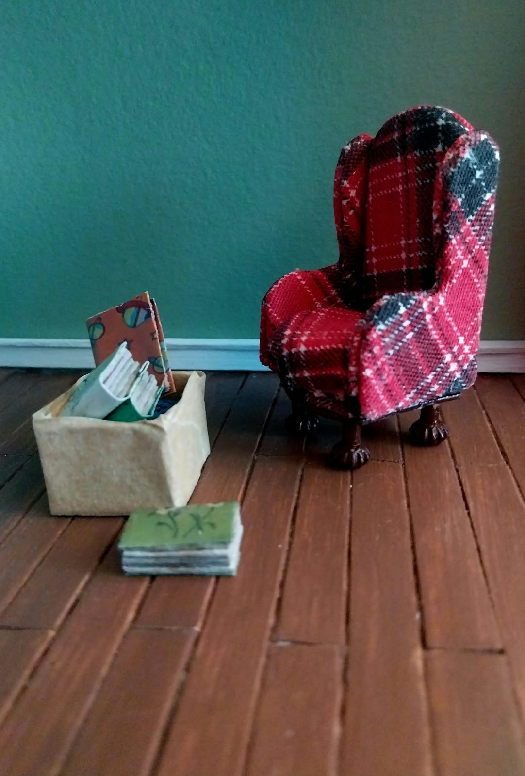 Poltrona clássica xadrez vermelha com caixa de livros em miniatura no atelier Madame Blum